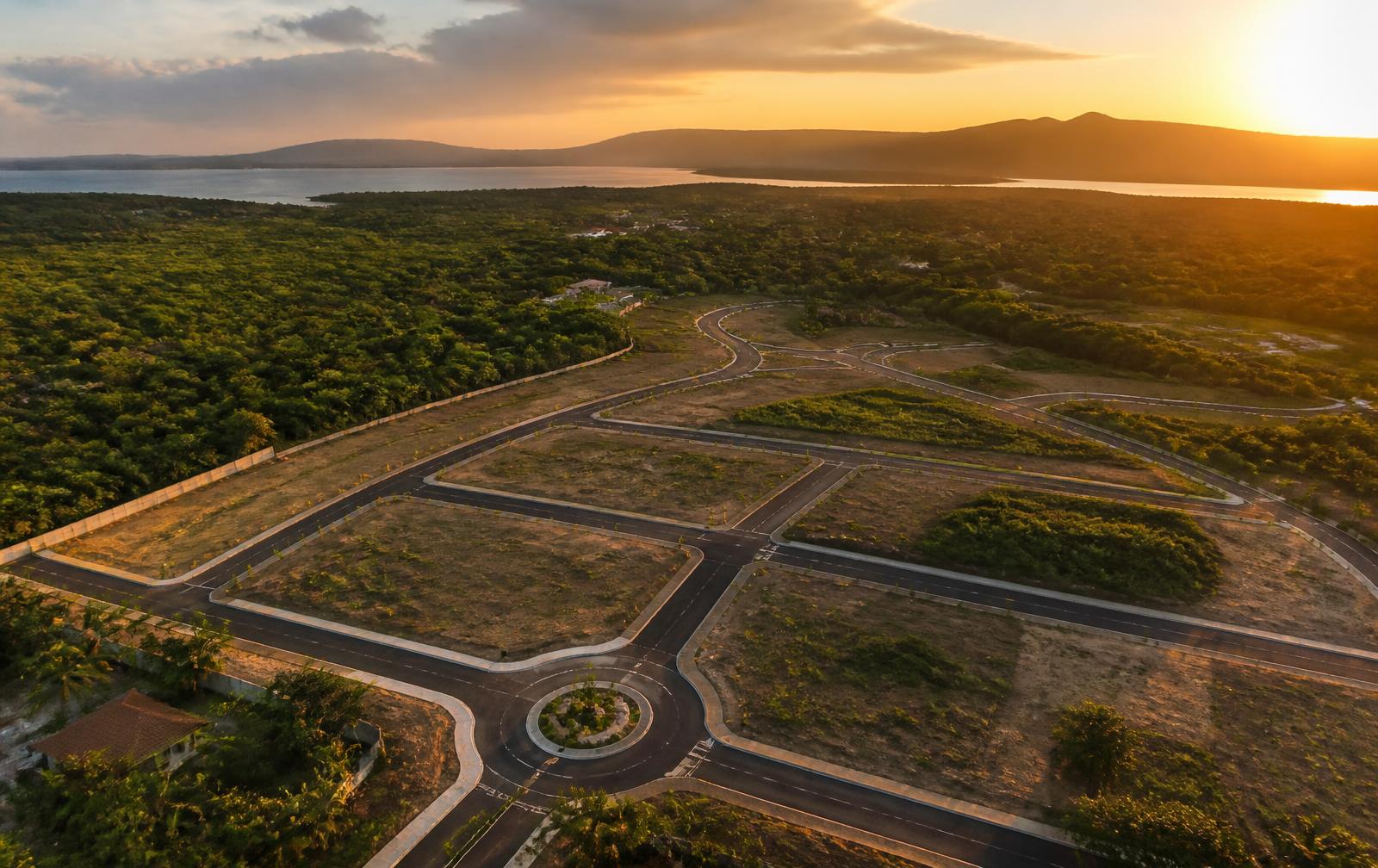 Vista aérea de calles pavimentadas y lotes delimitados al atardecer